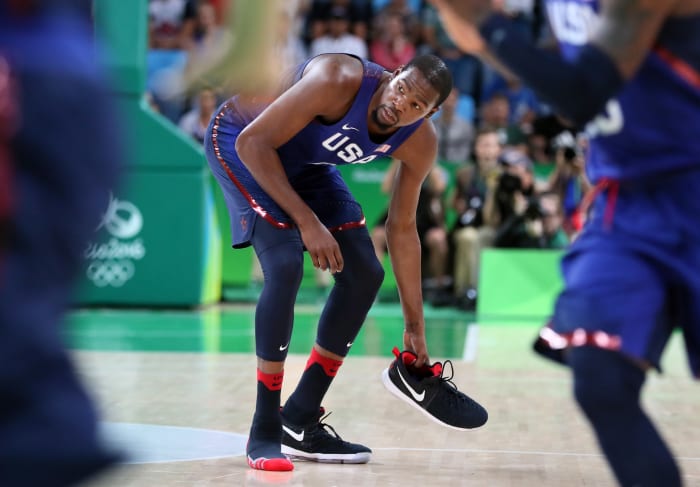 Team USA forward Kevin Durant picks up his shoe during a game.